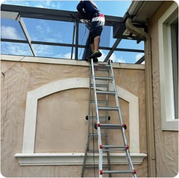 Working from a ladder on the upper panels of a pool cage